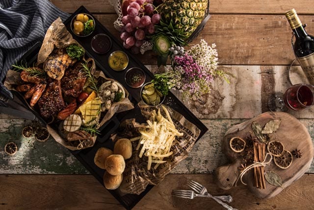 Catering-Auswahl mit Grill-Platte, Saucen und Brot auf rustikalem Holztisch